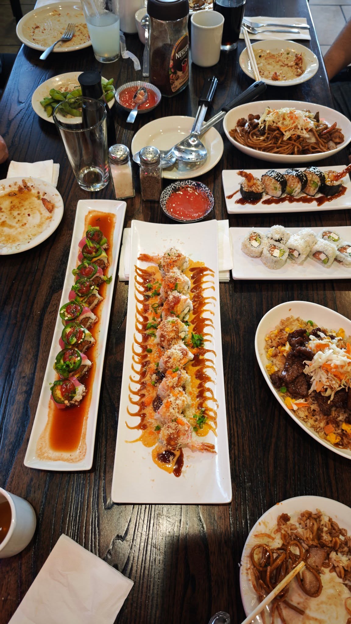 Full table spread showing sushi rolls, rice dishes, and entrees