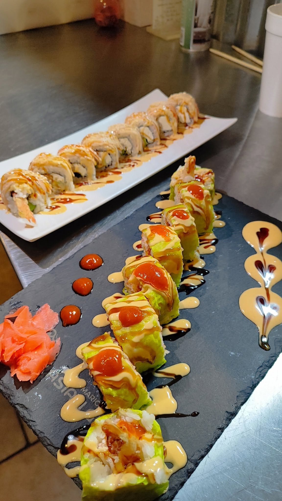 Two specialty sushi rolls on slate and white plates