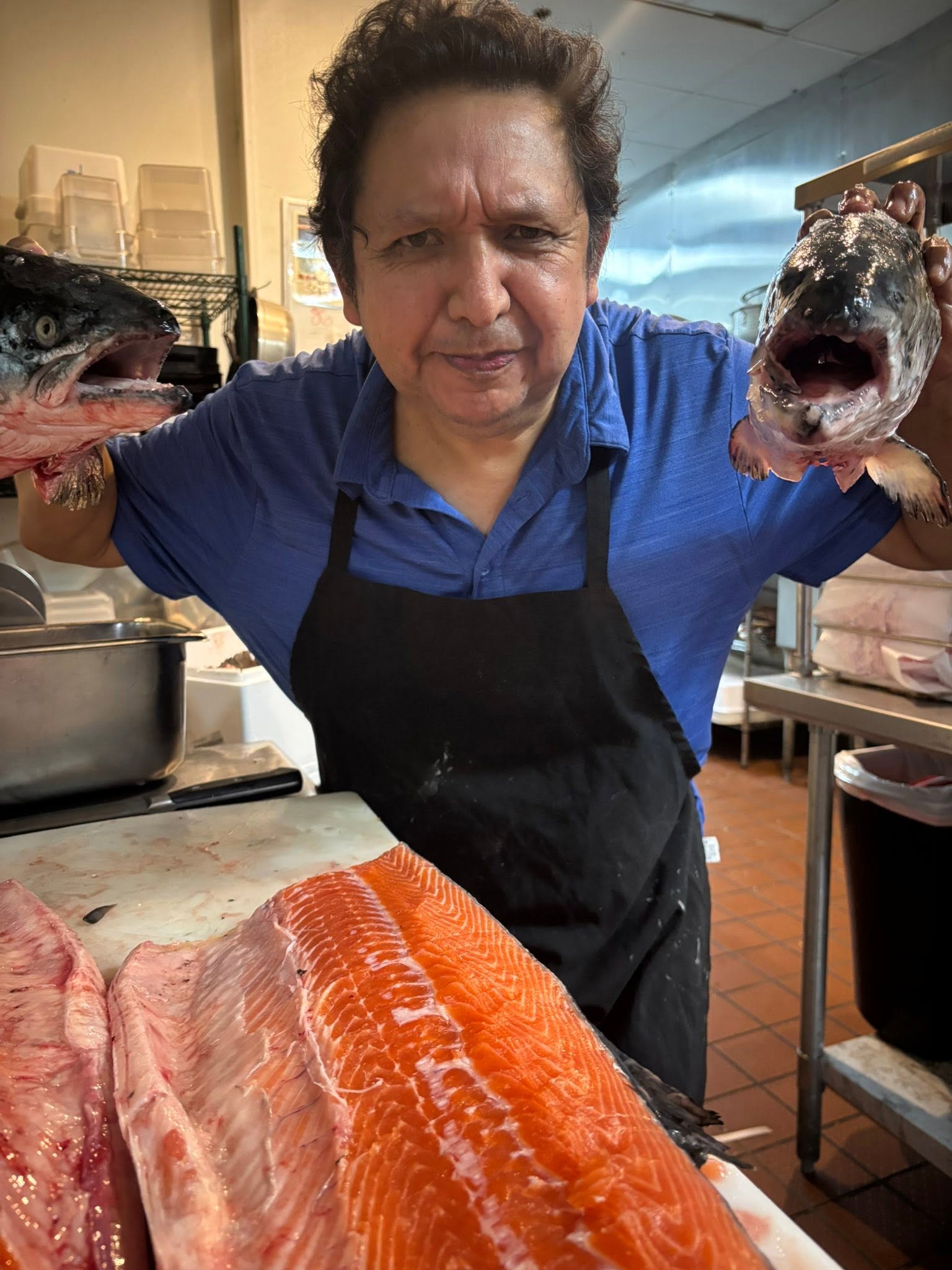 Mario holding fresh whole salmon fillets in the kitchen