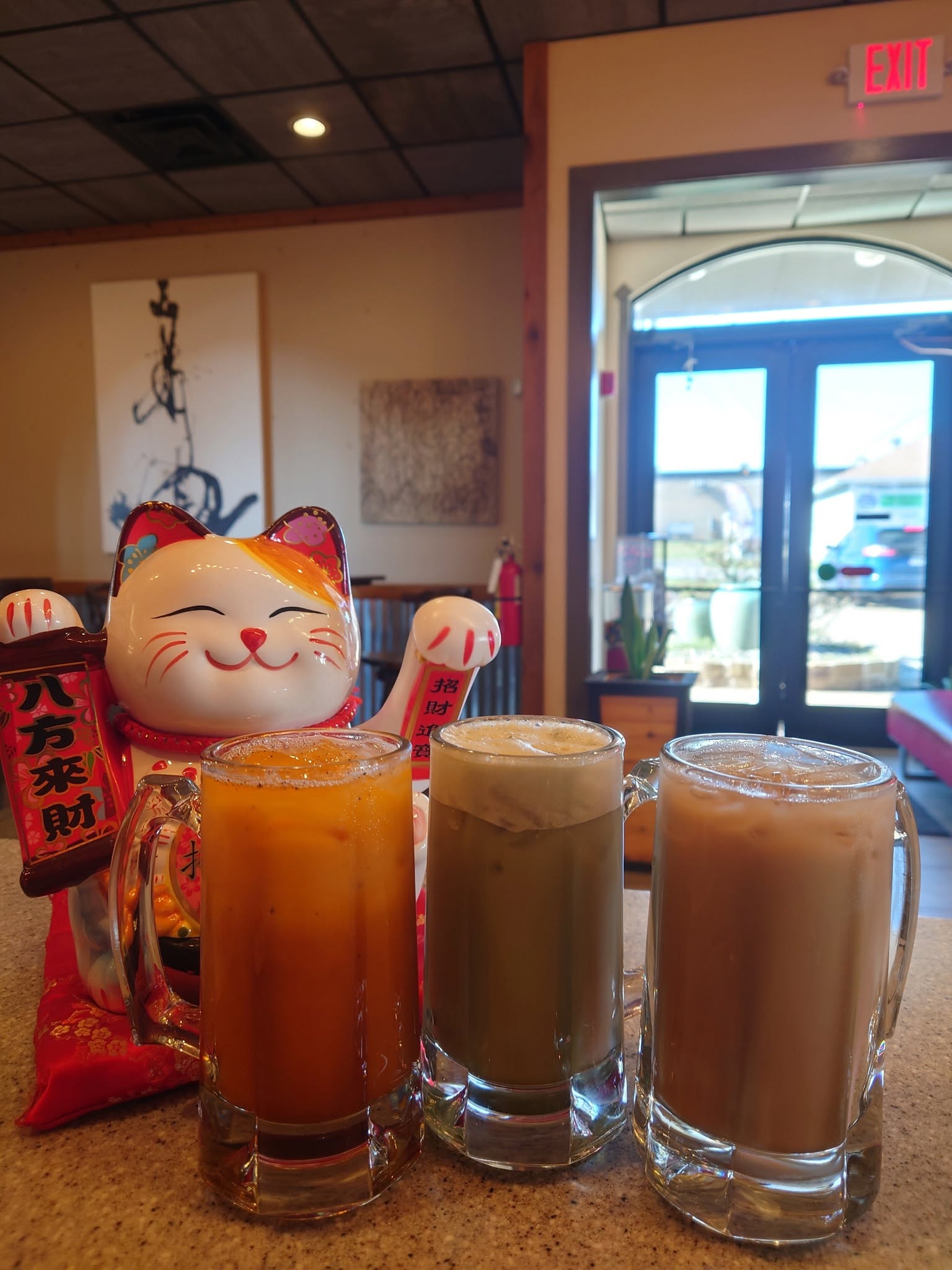 Lucky cat with Thai tea, matcha tea, and milk tea mugs